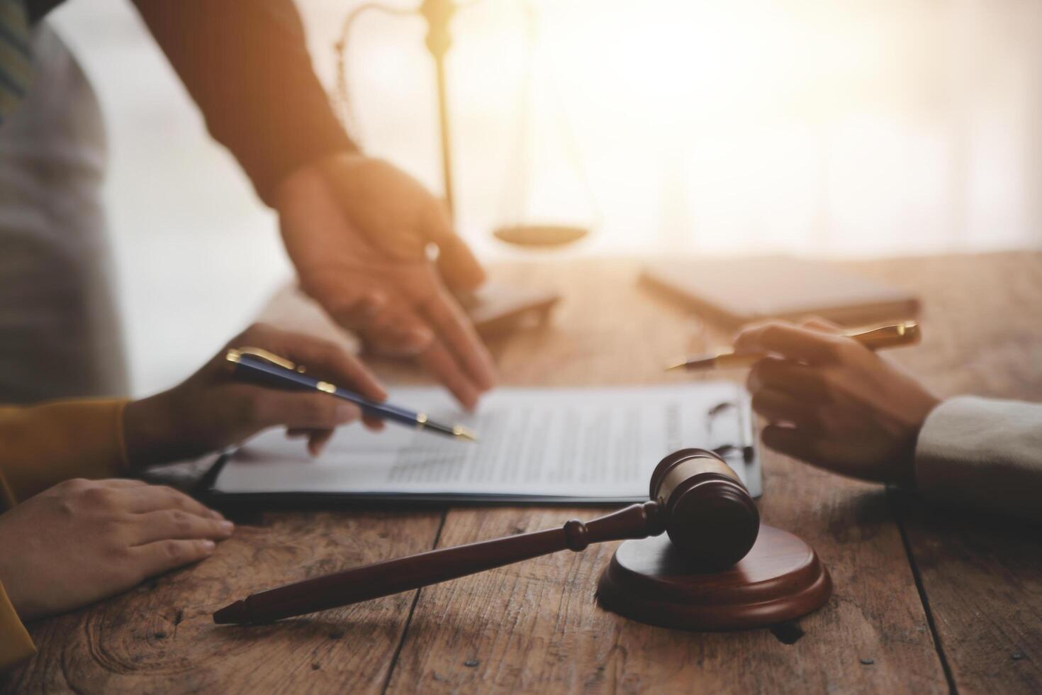 Business and lawyers discussing contract papers with brass scale on desk in office. Law, legal services, advice, justice and law concept picture with film grain effect photo