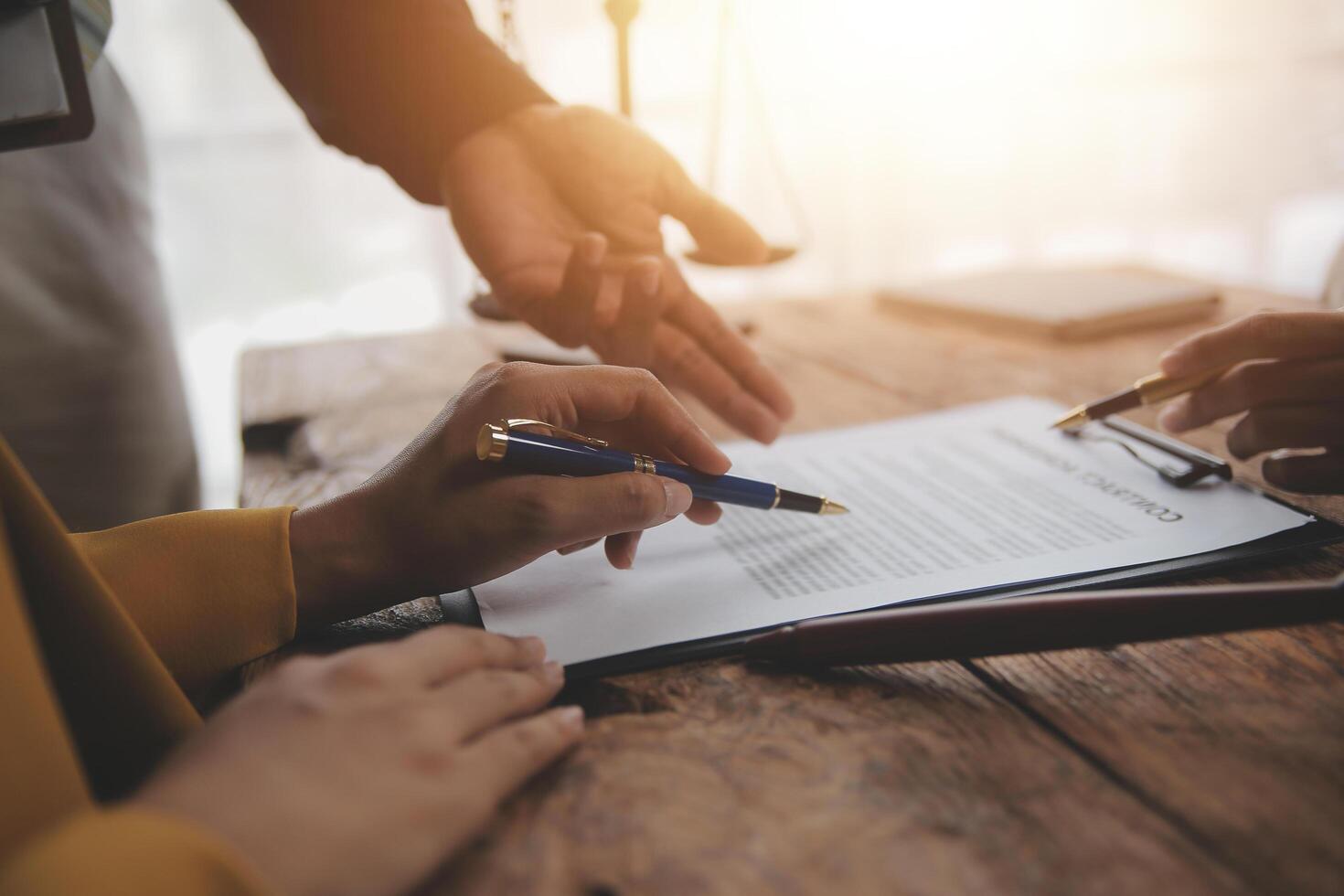 Business and lawyers discussing contract papers with brass scale on desk in office. Law, legal services, advice, justice and law concept picture with film grain effect photo