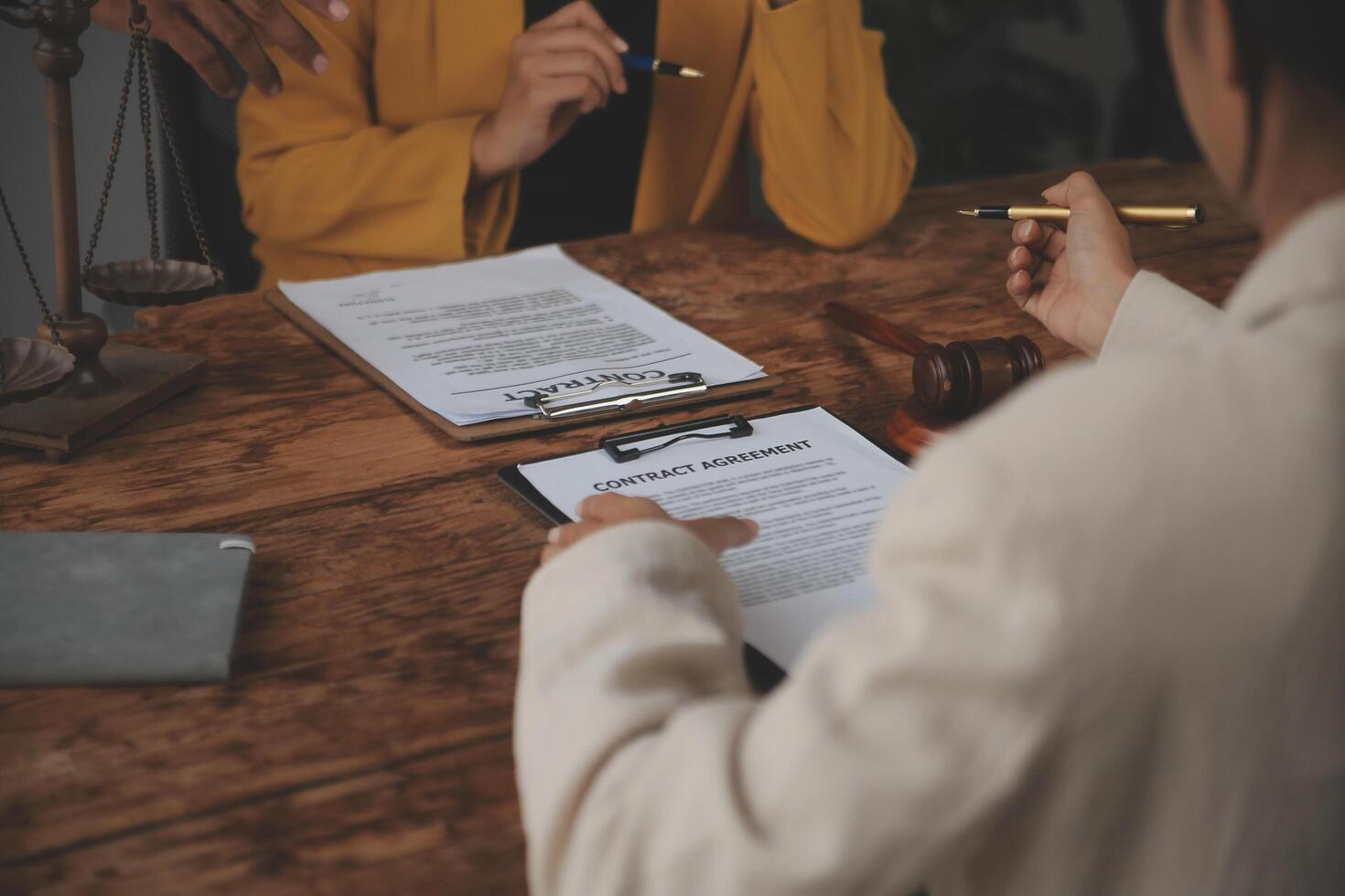 Business and lawyers discussing contract papers with brass scale on desk in office. Law, legal services, advice, justice and law concept picture with film grain effect photo