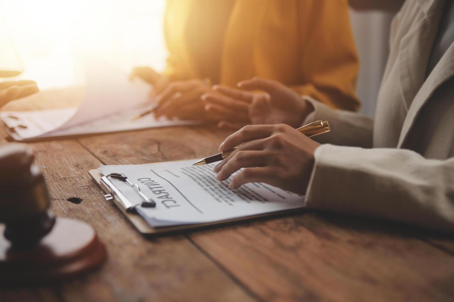 Business and lawyers discussing contract papers with brass scale on desk in office. Law, legal services, advice, justice and law concept picture with film grain effect photo