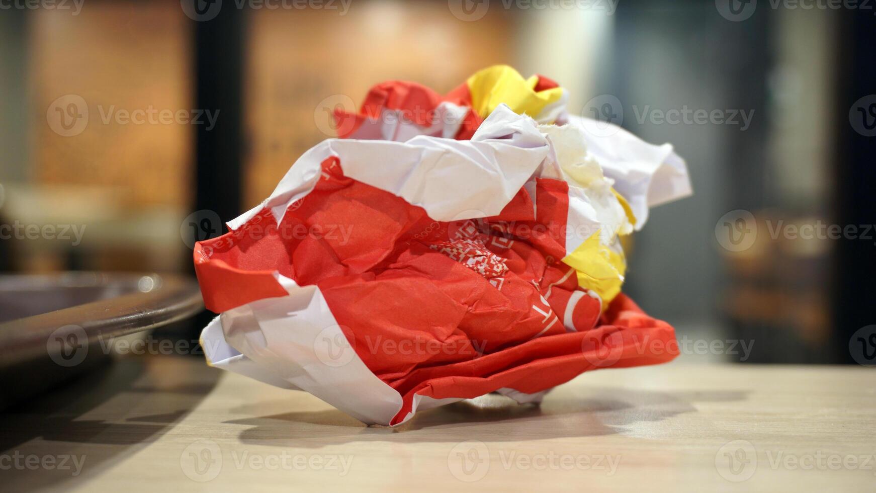 Crumpled red paper on table in coffee shop blur background with bokeh. photo