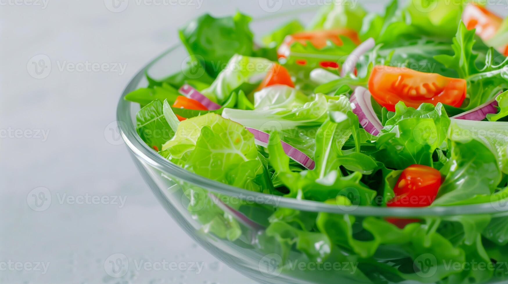 Fresh Green Salad with Lettuce, Cherry Tomatoes, and Red Onion in Glass Bowl on Light Background photo