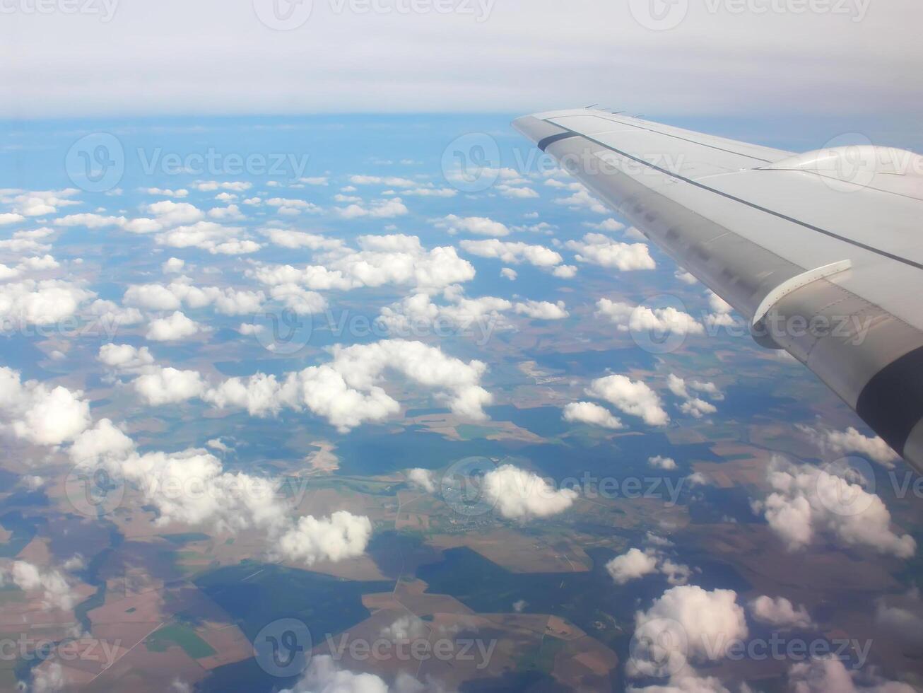 View from airplane window. White clouds above the land. photo