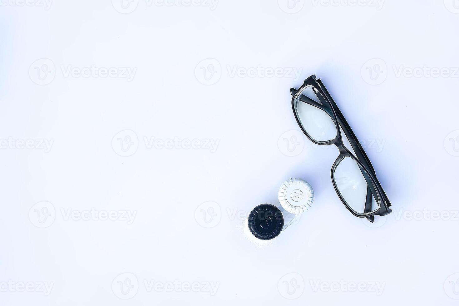 Top view of eyeglasses and contact lenses in container on white background. photo