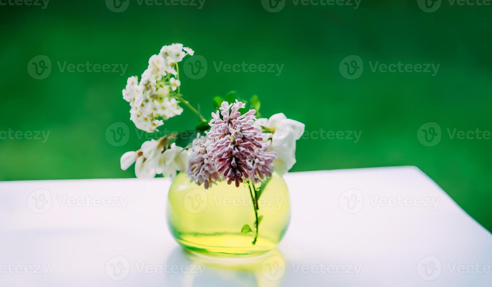 Bouquet of wildflowers in a small glass vase on the white table. photo