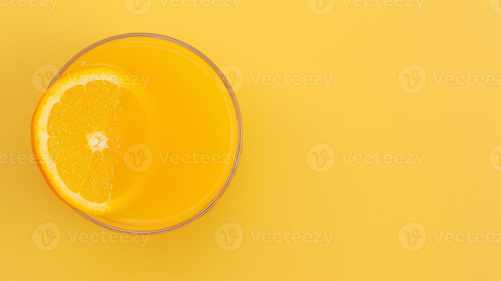 Overhead View of Fresh Orange Juice in a Glass with a Slice on Vibrant Yellow Background Reflecting Bright Citrus Themes and Refreshing Lively Design Elements for Summer or Health-Focused Concepts photo