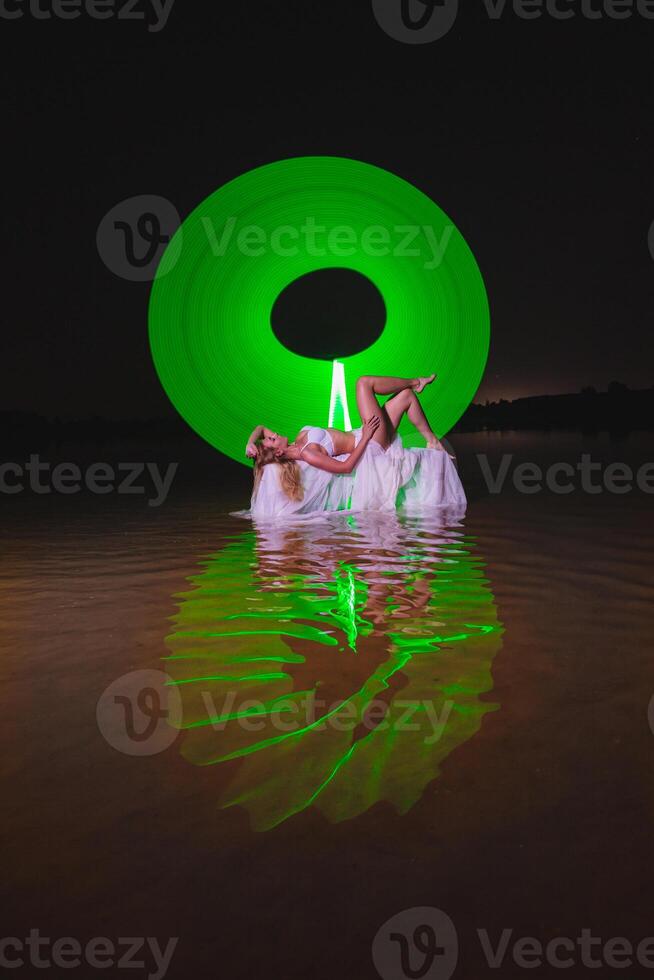 Young slim girl posing in water with abstract green light effect photo