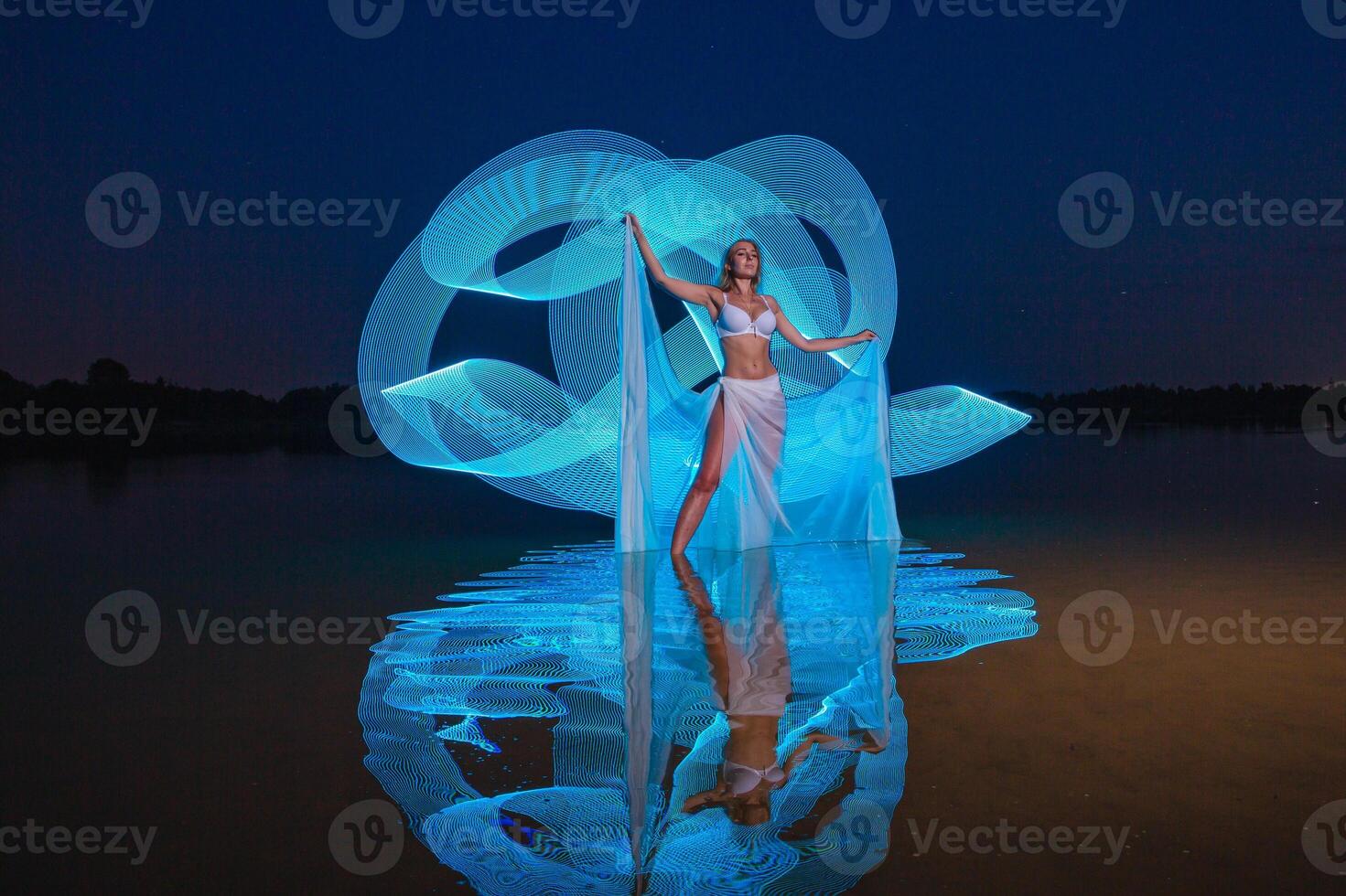 Young slim girl posing in water with abstract blue light effect photo