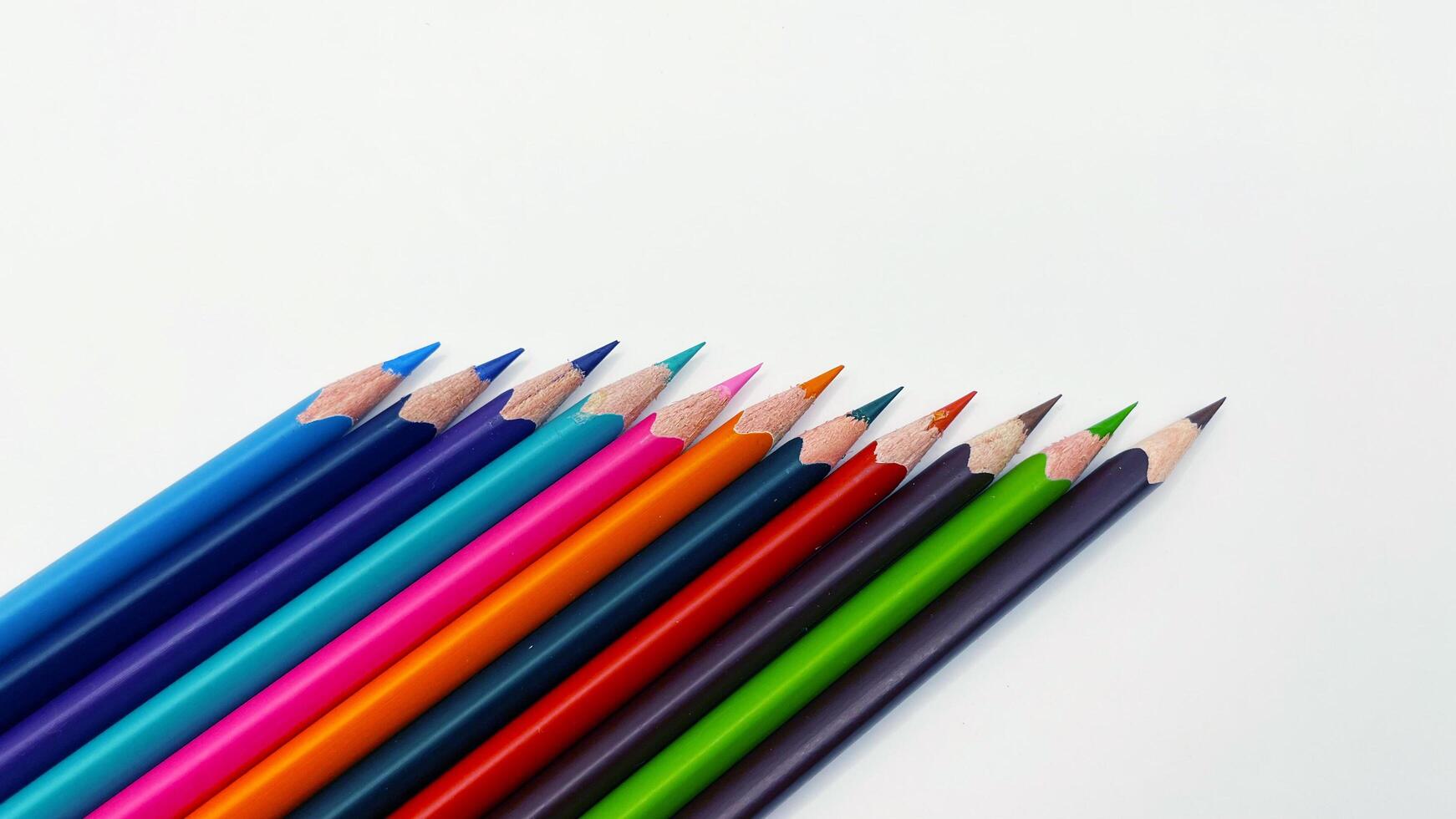 Colorful sharpened pencils are lined up on the table. photo