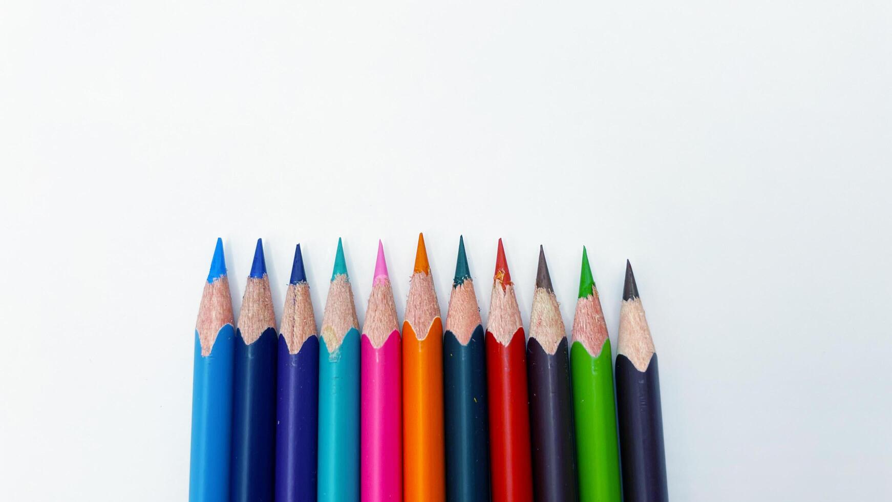Colorful sharpened pencils are lined up on the table. photo