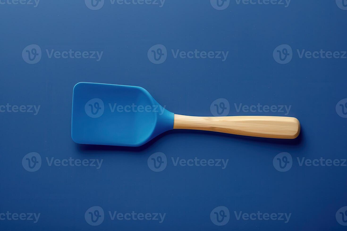 Blue silicone spatula with wooden handle on a dark blue background photo