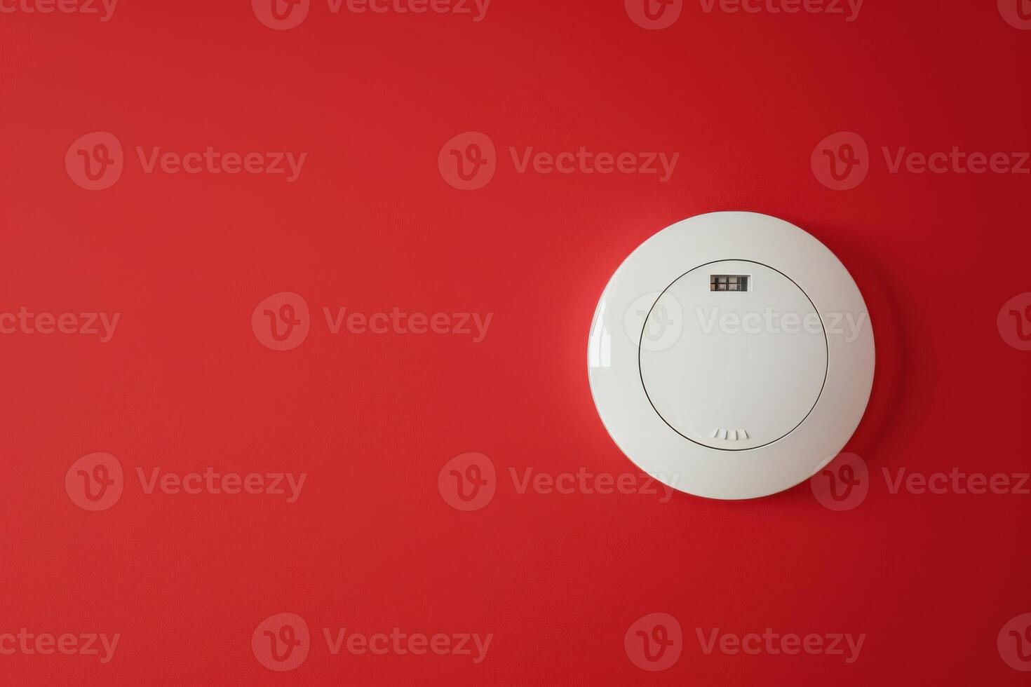 Circular smoke detector mounted on a vibrant red wall in a modern interior space photo