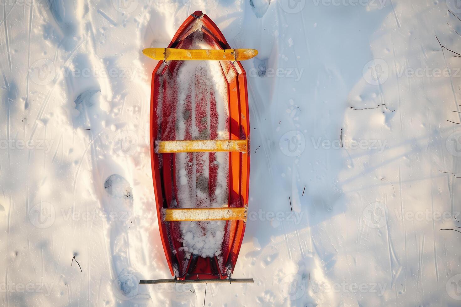 A red wooden sled rests on fresh snow in a winter landscape during midday photo