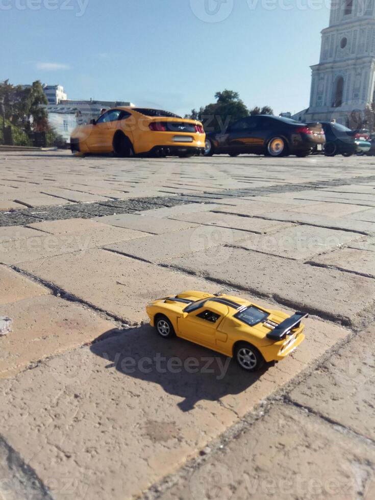 Toy yellow sports car stands on the ground in the background yellow sports car. Concept model of a stylish sports car. photo