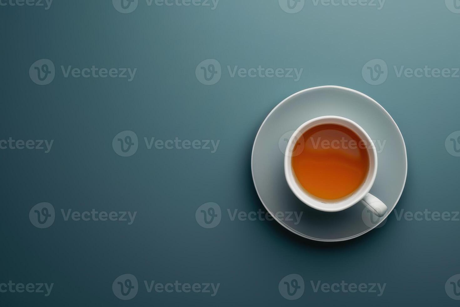 A steaming cup of tea on a simple saucer against a blue background photo