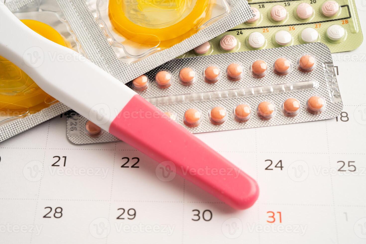 Pregnancy test and birth control pills on calendar, contraception health and medicine. photo