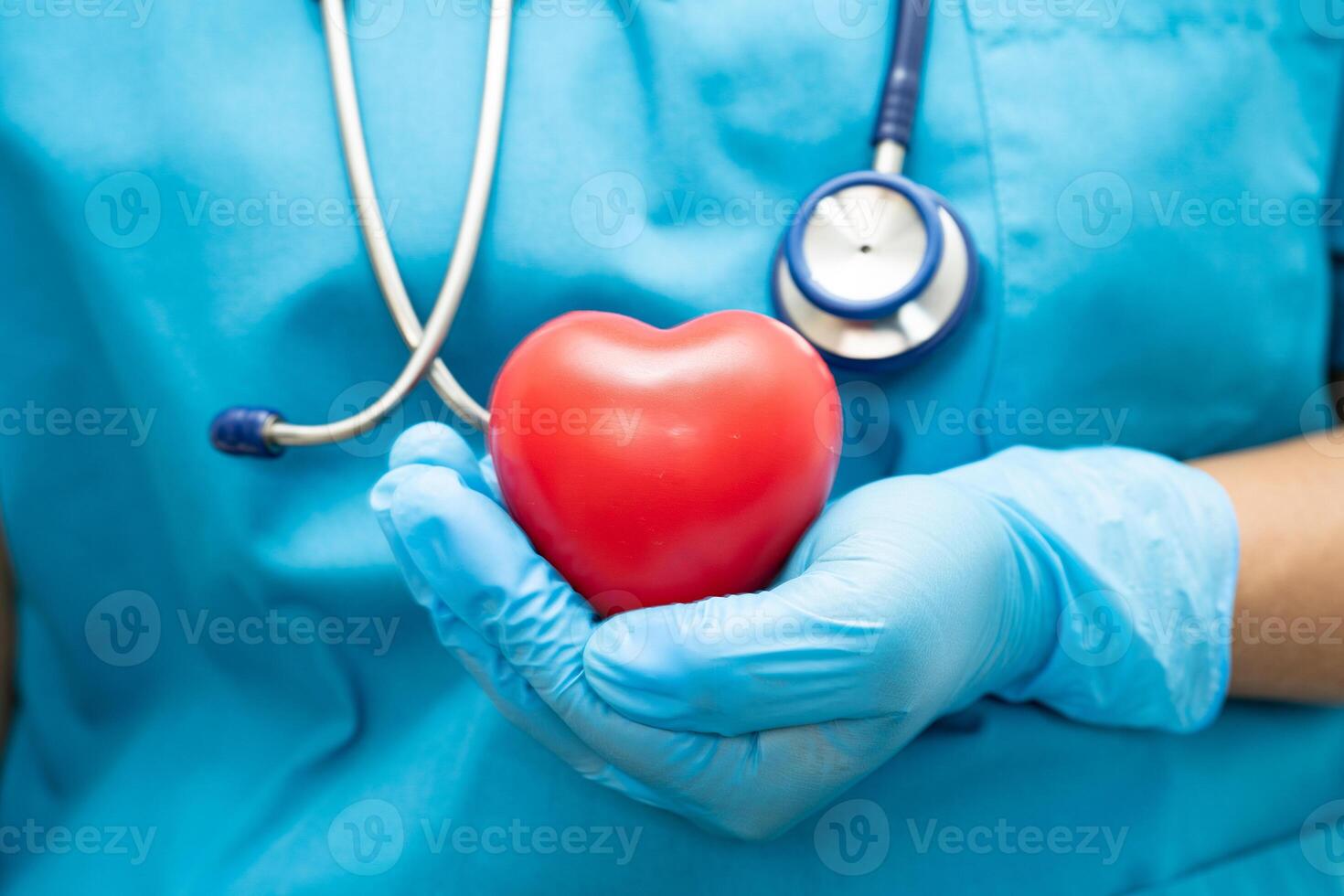 Doctor holding a red heart in hospital ward, healthy strong medical concept. photo