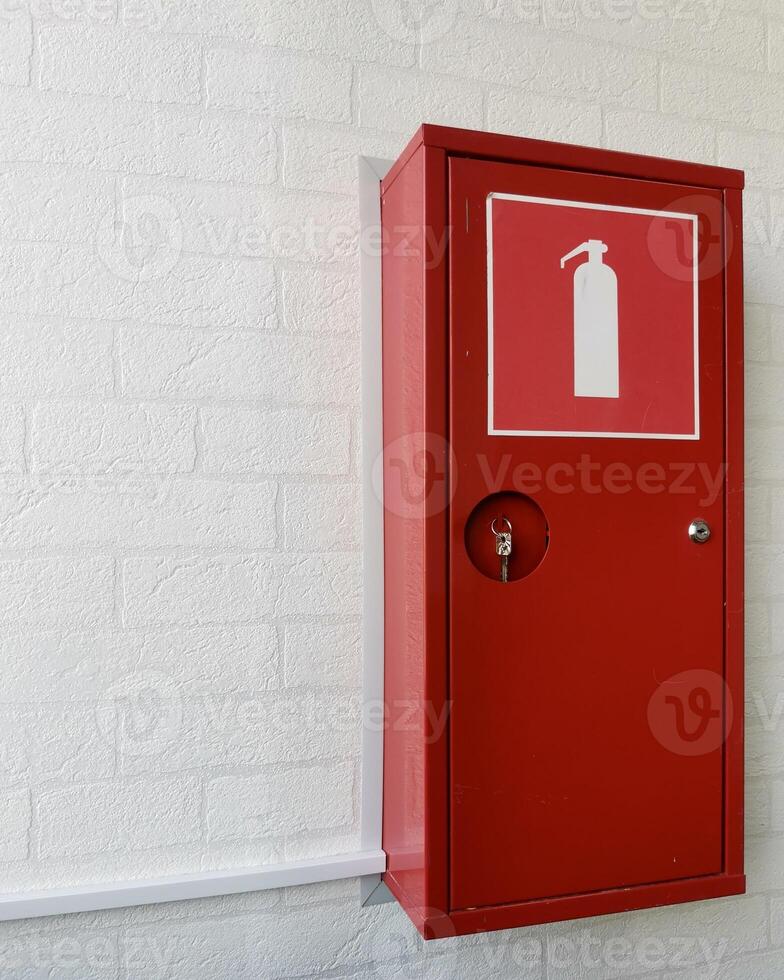 Red fire extinguisher cabinet mounted on a white brick wall. photo