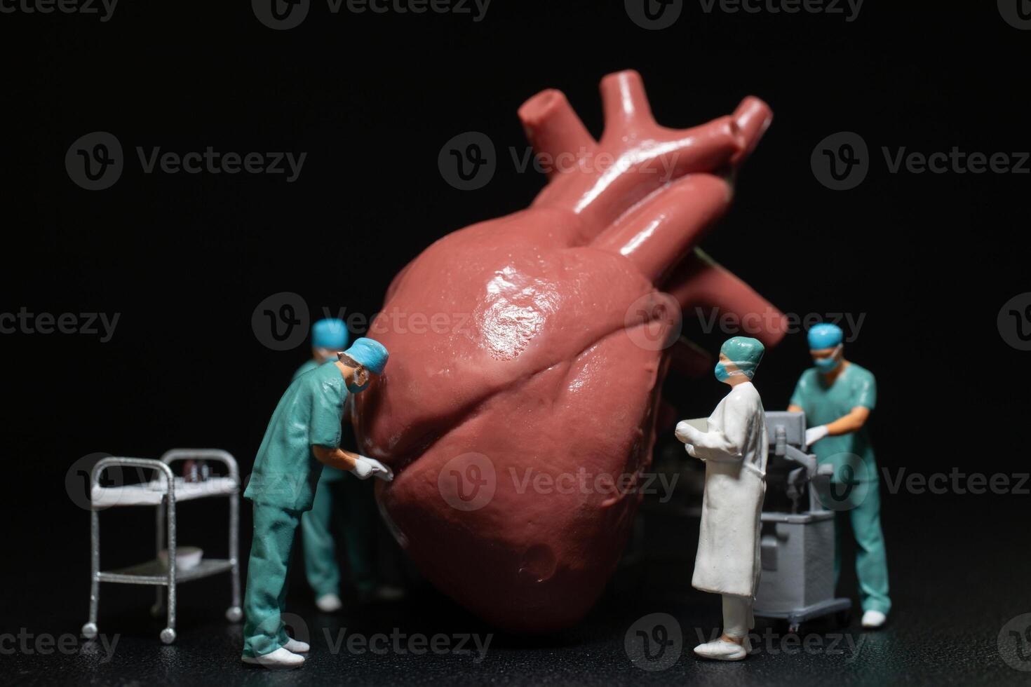 Miniature medical professionals performing a procedure on a large, anatomically accurate heart model. photo