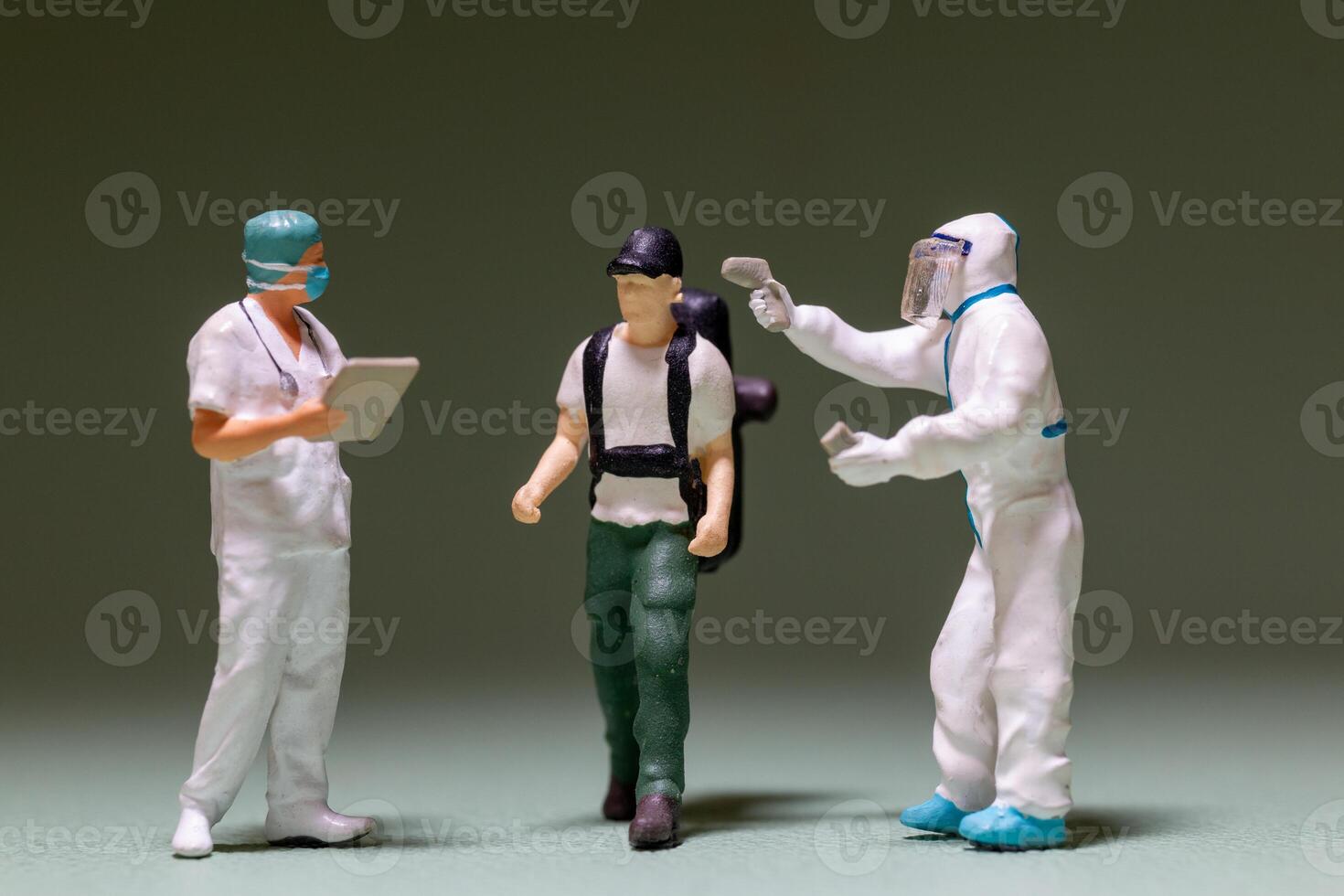 A miniature scene depicts a traveler being screened by healthcare workers photo