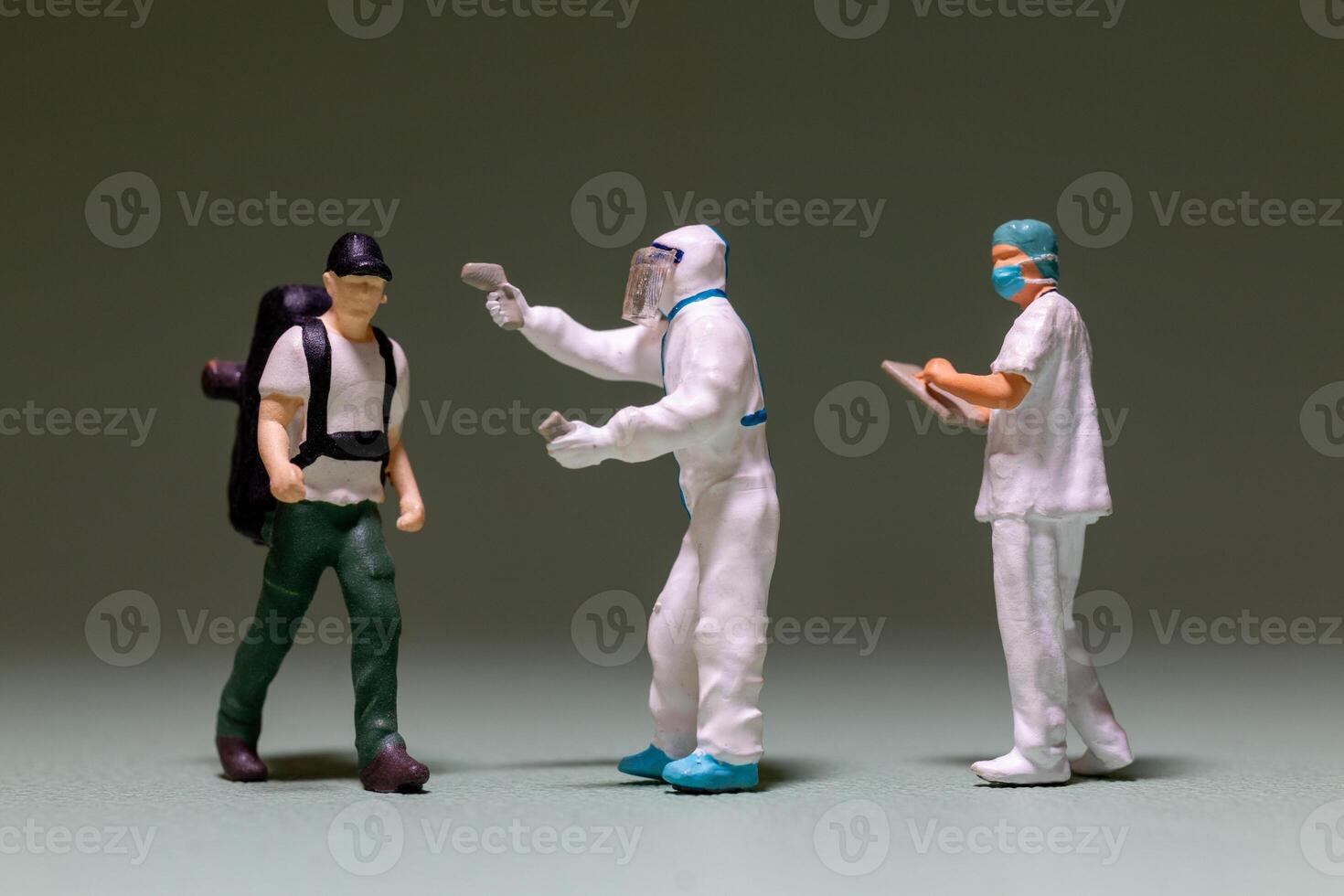 A miniature scene depicts a traveler being screened by healthcare workers photo
