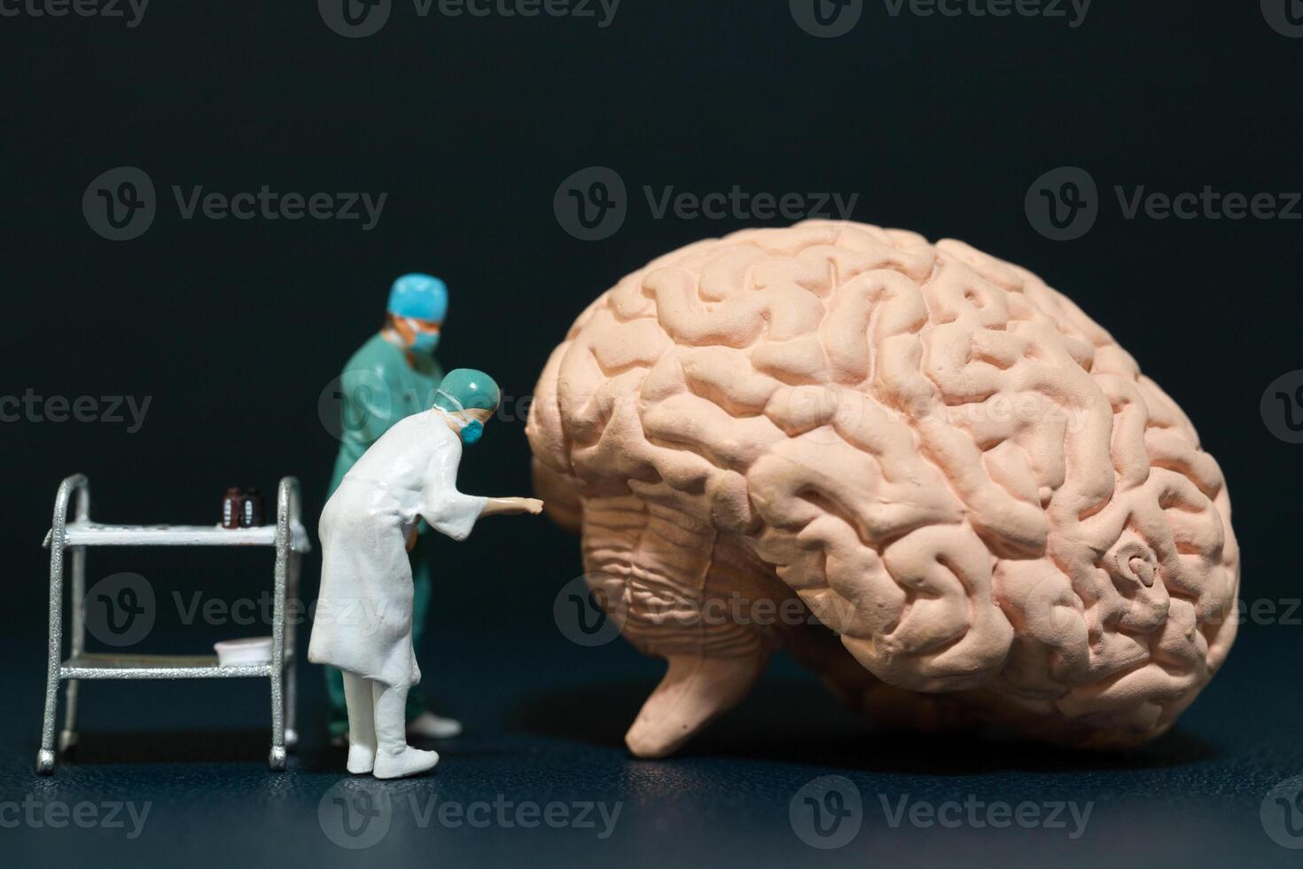 Miniature people of surgeons examining a large brain model photo