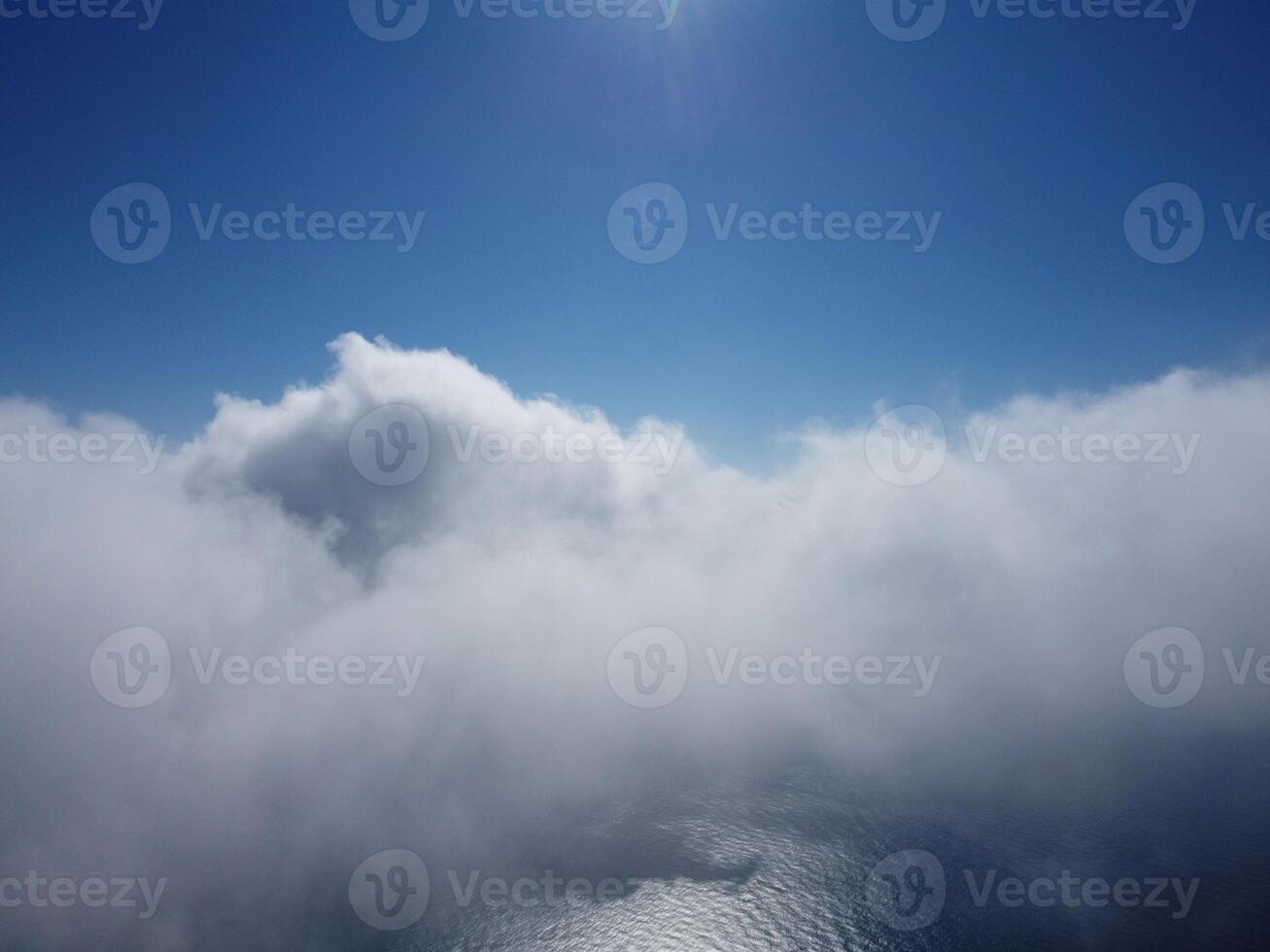 Aerial view. The drone flies over foggy and fluffy clouds. Blue sky sun and sea fog. Abstract aerial nature summer ocean sunset sea and sky background. Vacation, travel and holiday concept photo