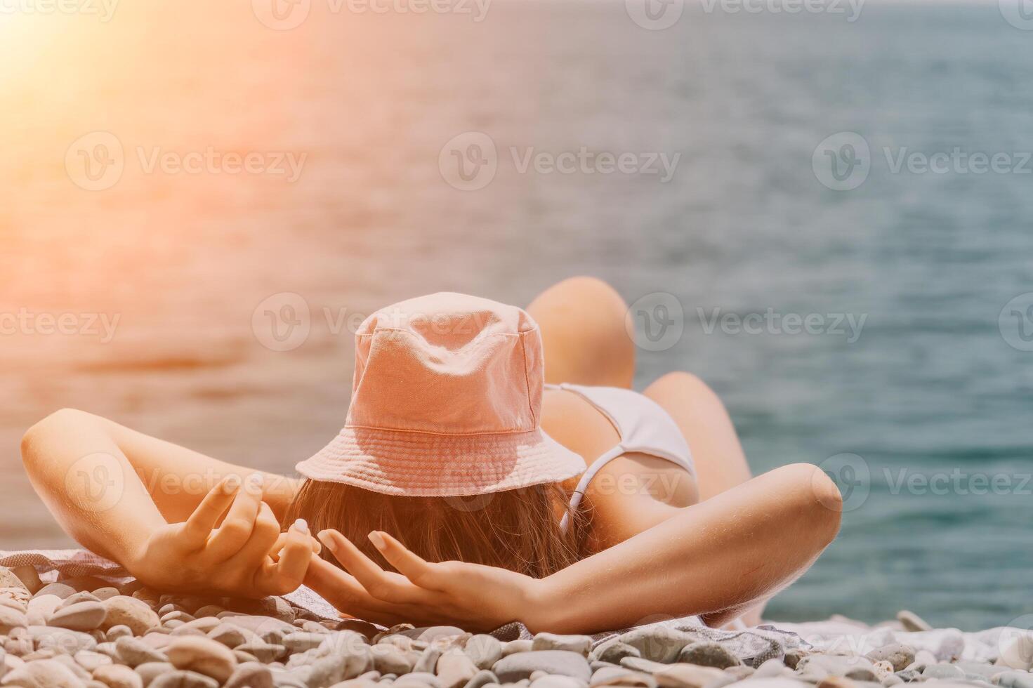 Unrecognizable positive woman in white bikini sunbathing or tanning on seaside beach during summer. Slow motion of happy tourist enjoying sun tan lying on beach chair lounge at luxury resort photo