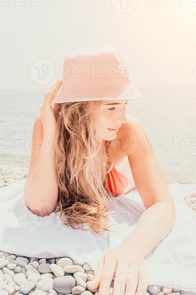 Happy young woman sunbathing or tanning on a seaside beach during summer vacation. smiling tourist in red swimsuit enjoying sun tan lying on beach near to calm clear sea water. photo