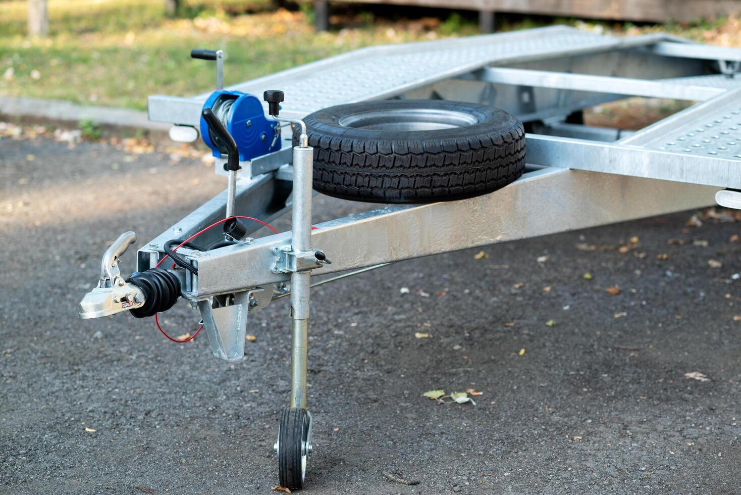 A close-up of a metal trailer hitch with a mounted spare tire and a manual winch. photo