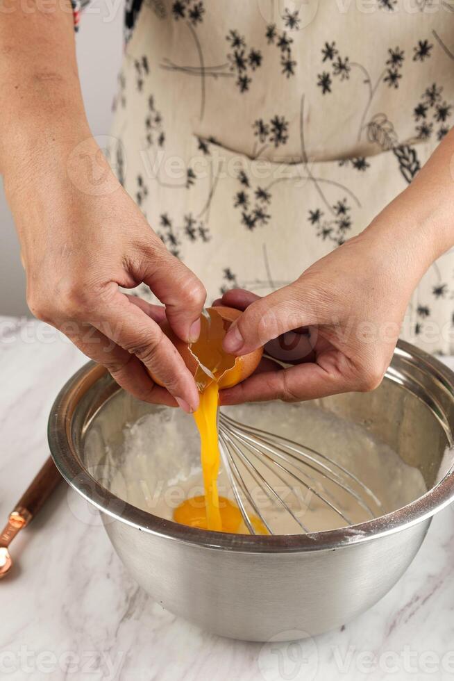 Woman Hands are Breaking Eggs for Baking on the Table photo