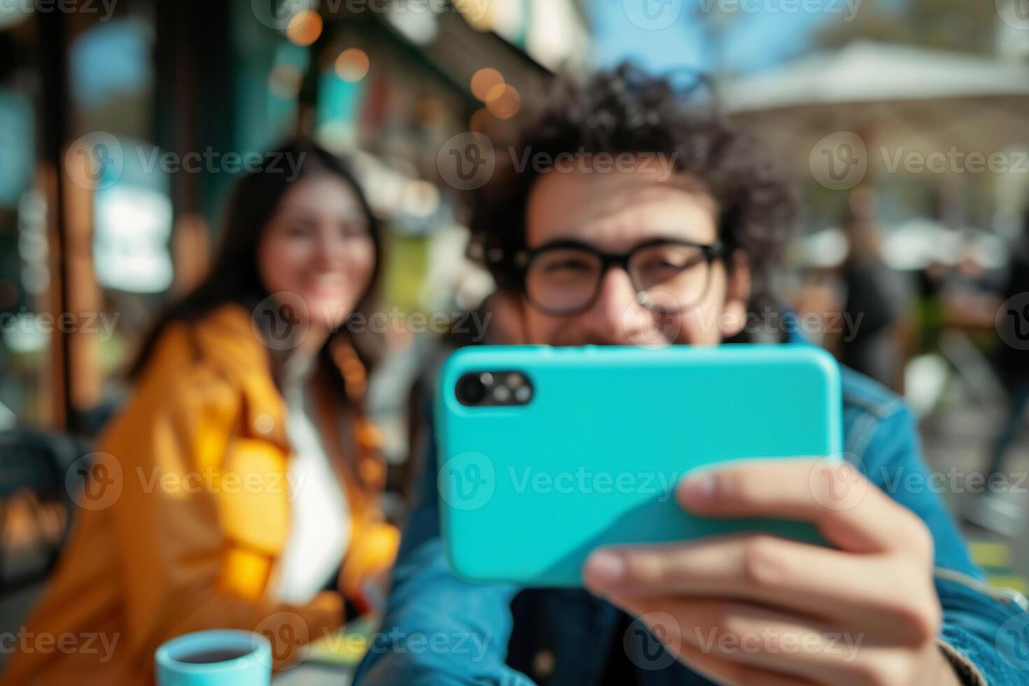 A man enjoys a moment taking a selfie with tea as his wife laughs in the background photo