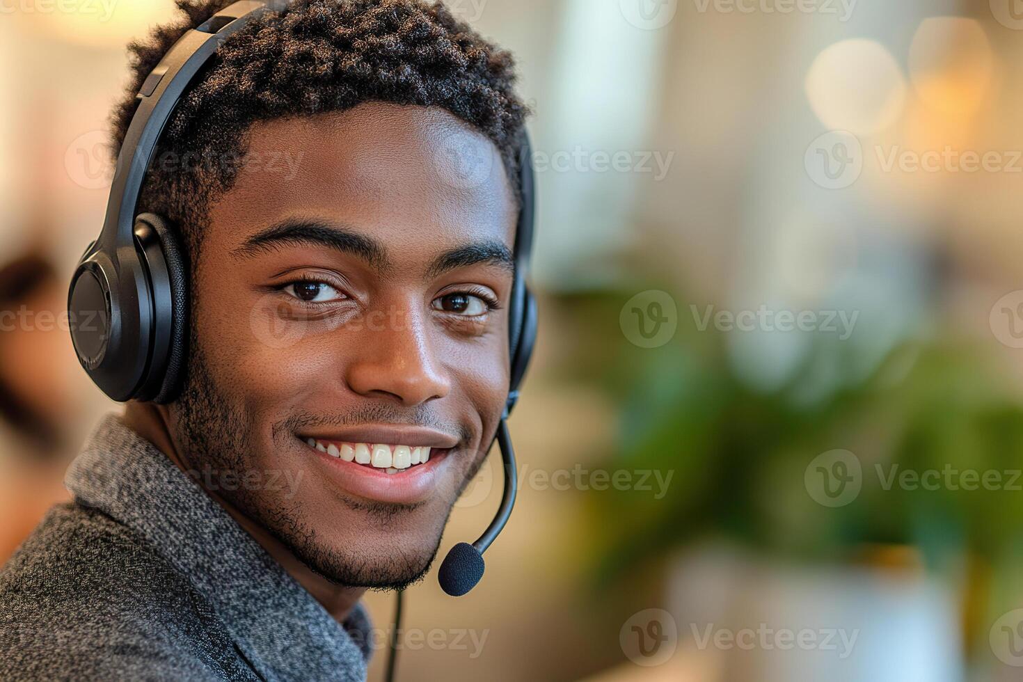 young black male consultant wearing a headset smiles in a contact center photo