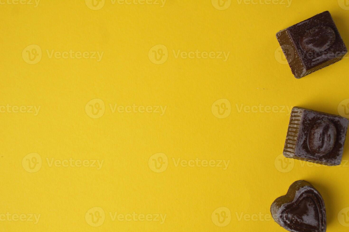 Chocolate candies on a yellow background top view with space for text and copyspace. Food Background photo