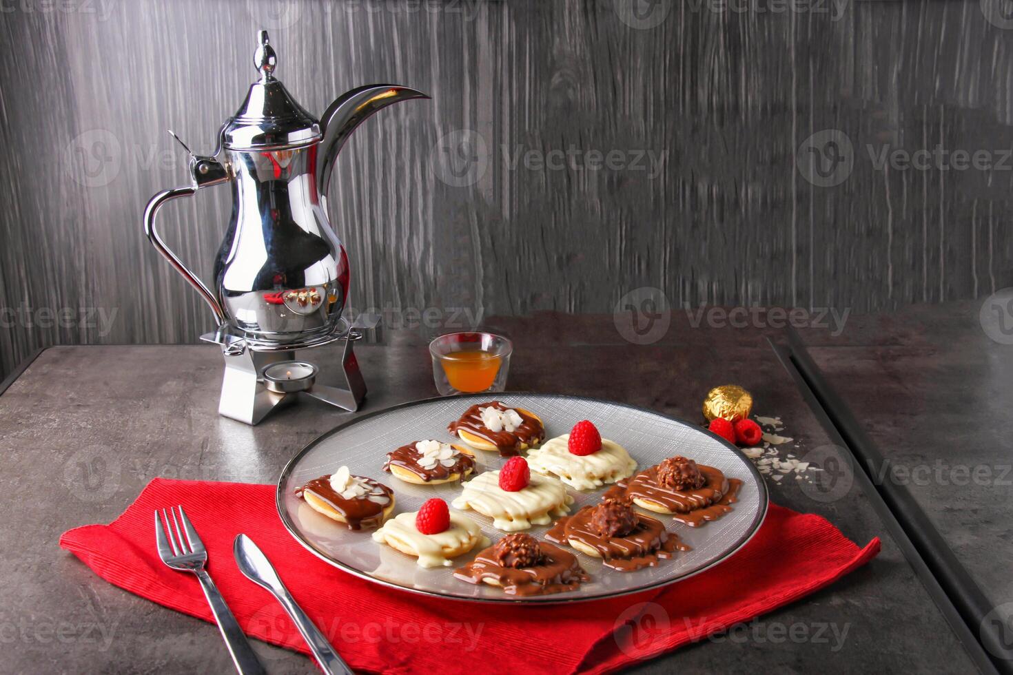 Romantic mix Mini Pancake Platter topped with chocolate, white chocolate, raspberries, almonds, and chocolate candy balls with arabic coffee served in plate isolated on napkin side view of dessert photo