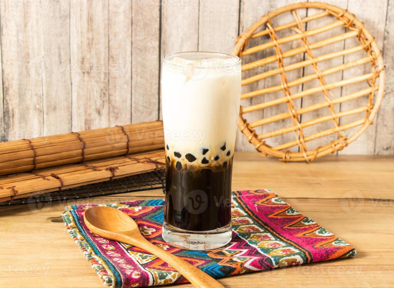 Ice Brown sugar pearl milk tea or boba milk with wooden spoon served in glass isolated on napkin side view of taiwan iced drink photo