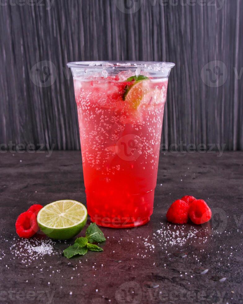 Refreshing Raspberry Mojitos made with lime juice, mint leaves, and sparkling water served in glass isolated dark background side view of healthy drink photo