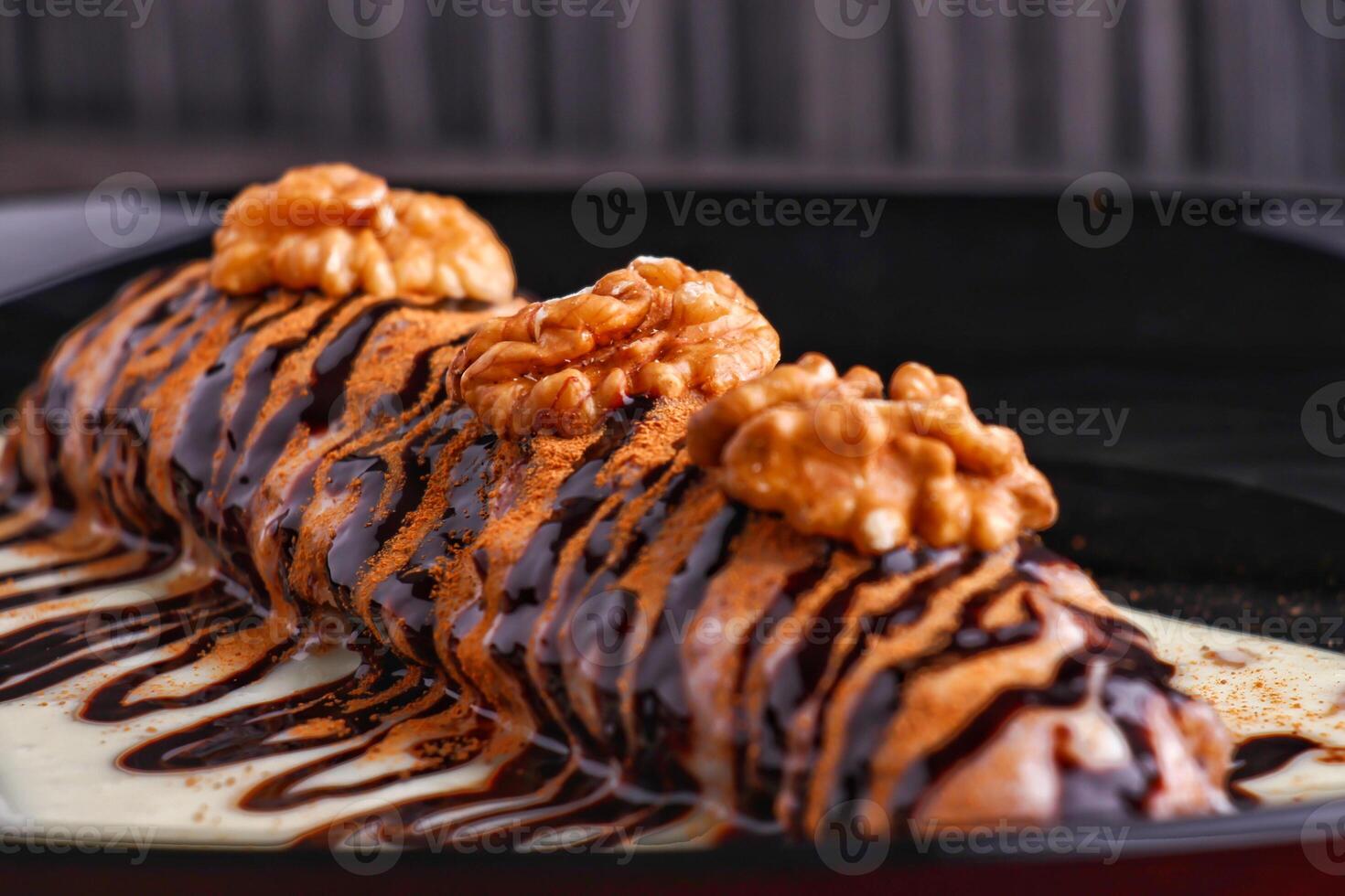 Decadent Chocolate Walnut Cinnabon Roll with Drizzled Sauce served in plate isolated on dark background closeup side view of dessert photo