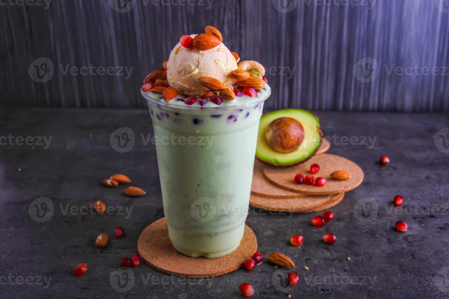 Creamy Avocado Smoothie with Nuts, Pomegranate seeds, and vanilla ice cream scoop served in glass isolated on background side view of healthy and delicious beverage photo
