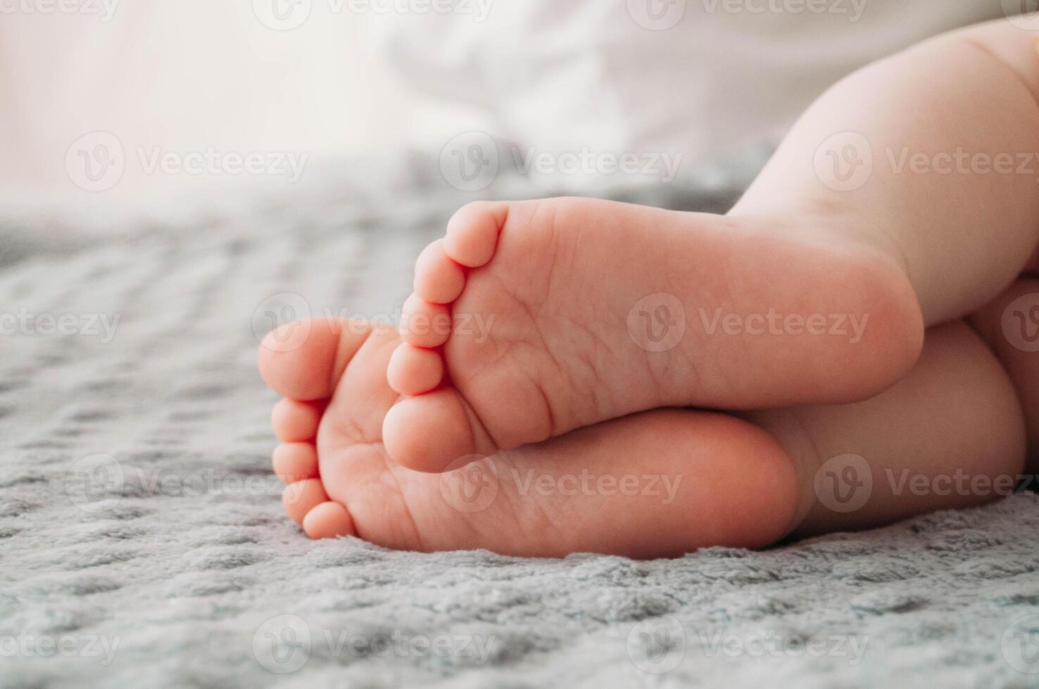 Children's bare feet on the bed, on the gray blanket. Photo of Cute feet of a sleeping baby.