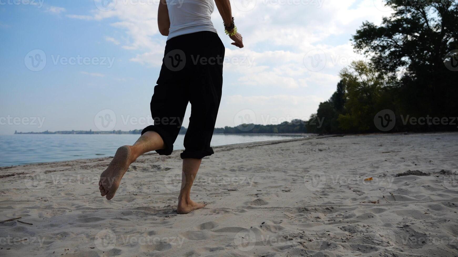 Bare feet of adult woman jogging on sand at the beach with seascape at background. Female legs running along sea shore. Happy lady spending time near ocean coast. Concept of summer vacation photo