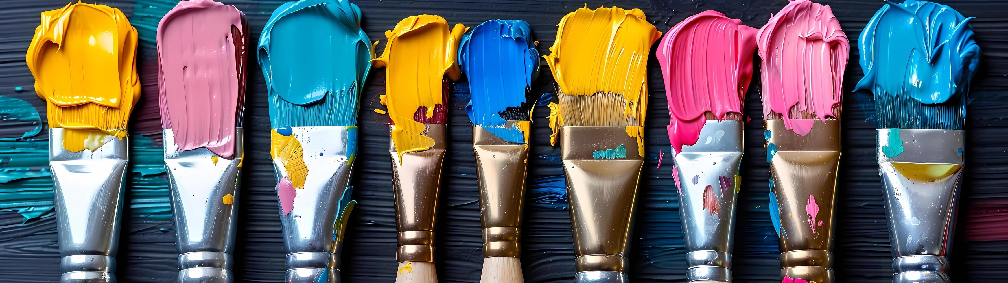 A collection of vibrant paintbrushes dipped in various acrylic paints lies on a dark background in a flat lay, symbolizing artistic creativity photo