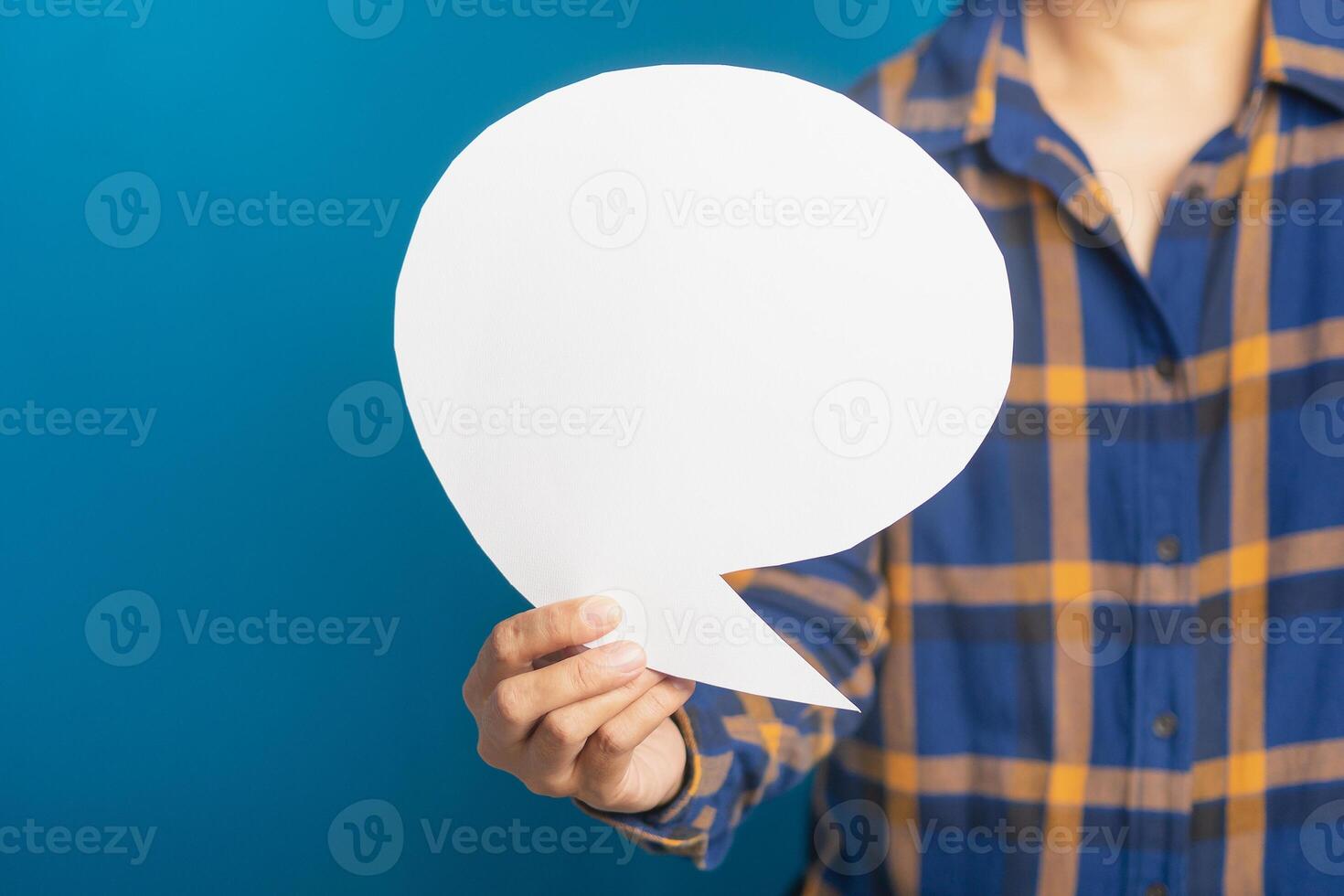 Question mark speech bubble concept. Midsection of a man holding a blank paper while standing with blue background in the studio. Space for text. Talking and message for social media concepts ideas photo