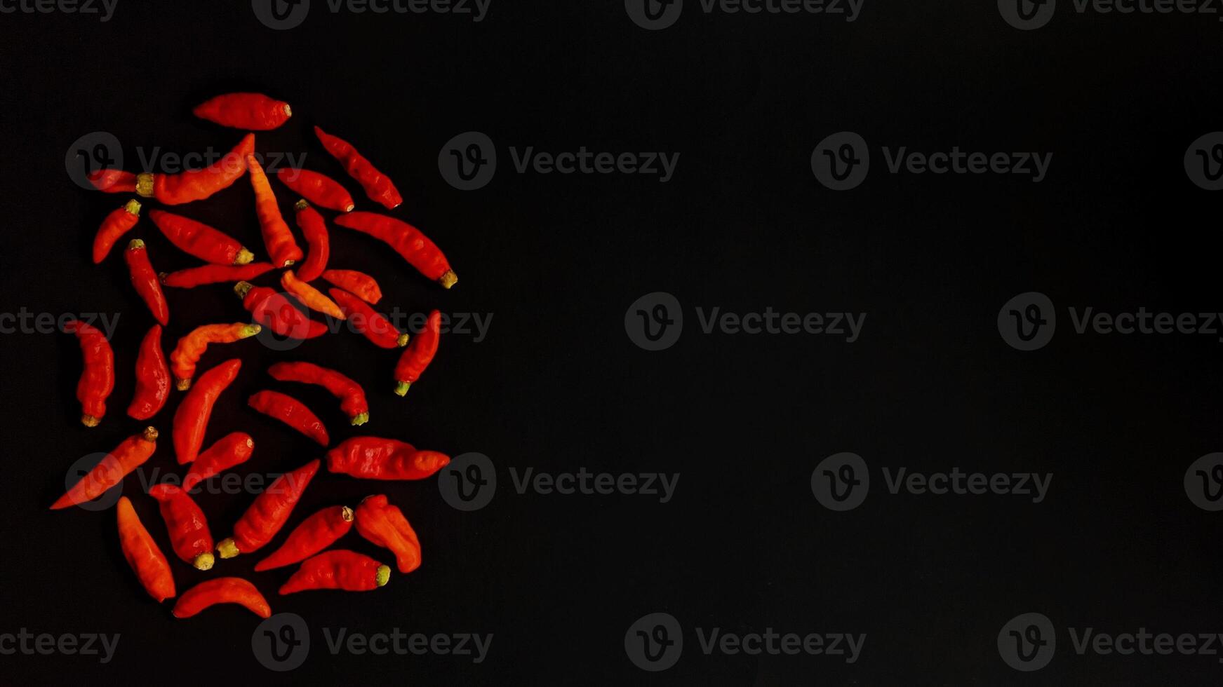 A group of red peppers on a black background with negative space photo