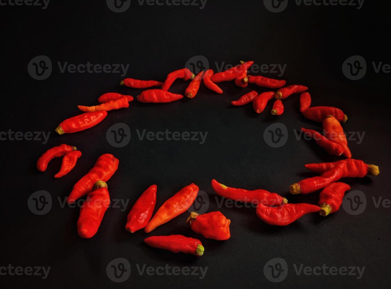 Front view of circle of red hot peppers on a black background photo