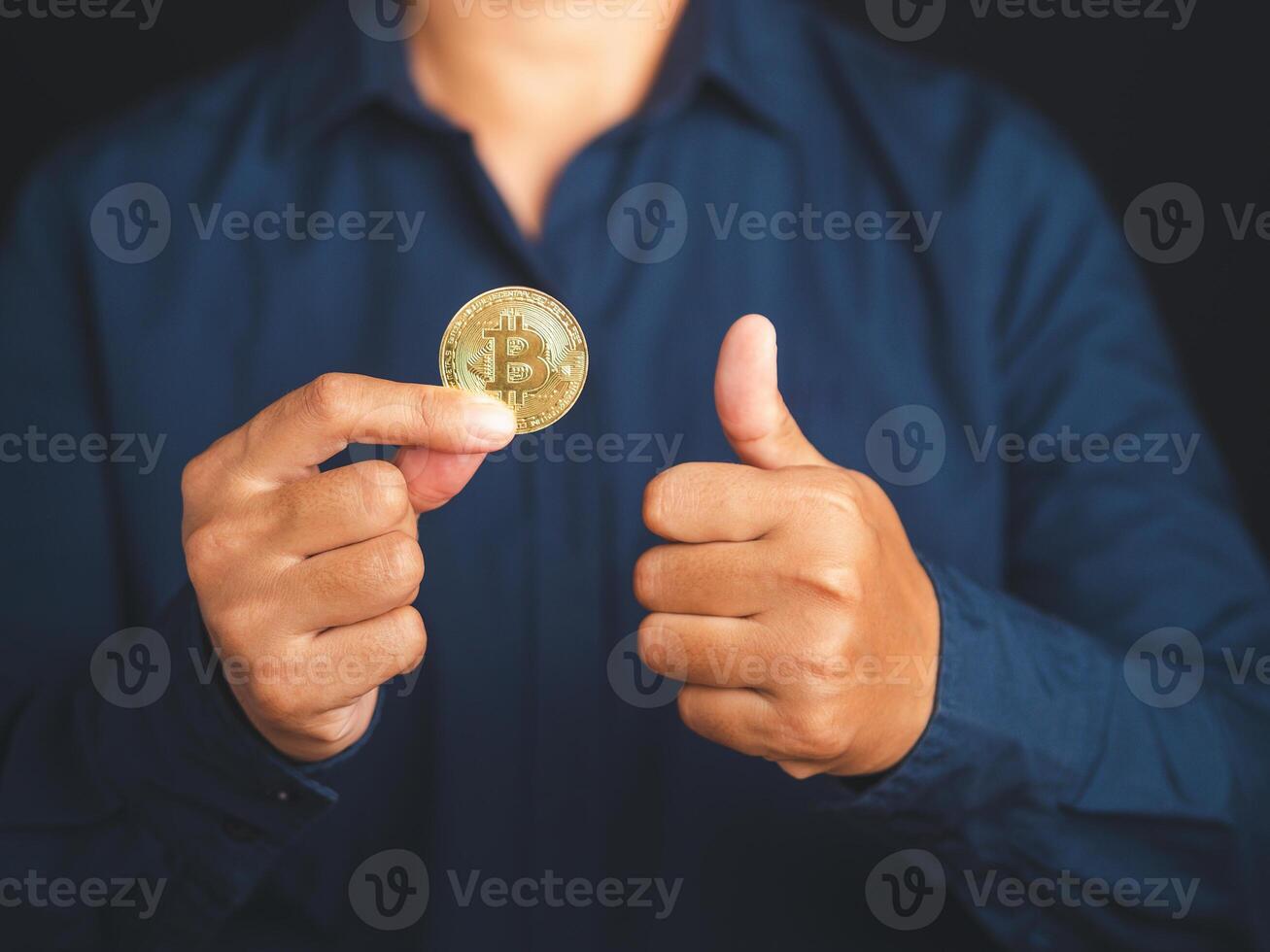 Investor hand holding a bitcoin coin and show thumbs up while standing with a black background. Bitcoin is a symbol of cryptocurrency, electronic virtual money. blockchain technology and asset digital photo