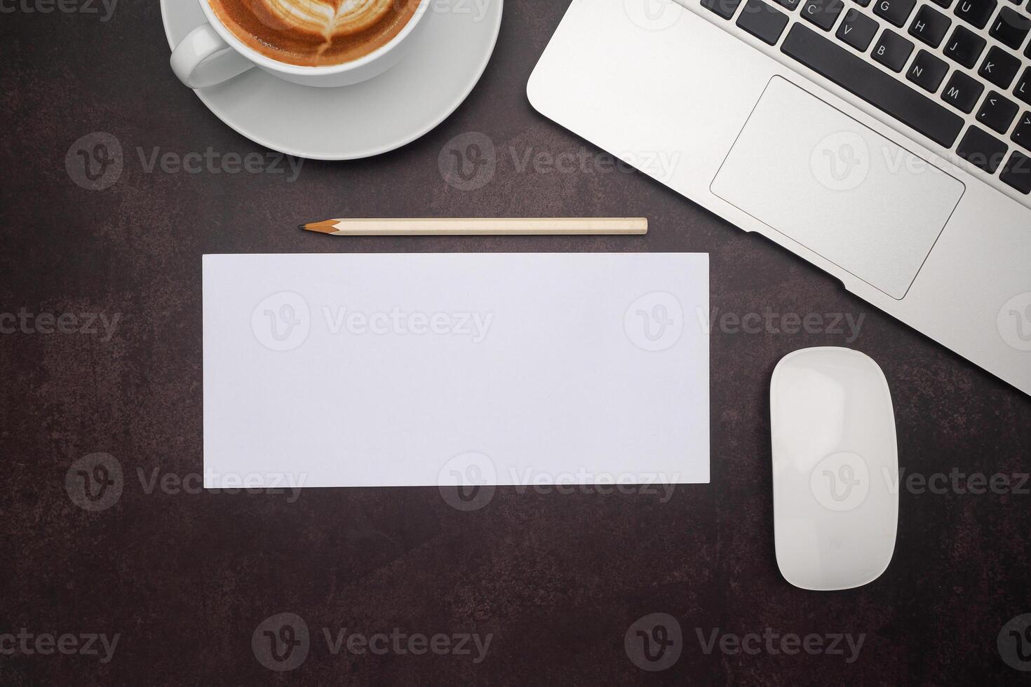 Top view of white paper or envelope and a pencil with a laptop, mouse, and a coffee cup on the desk in the office. Vintage background photo