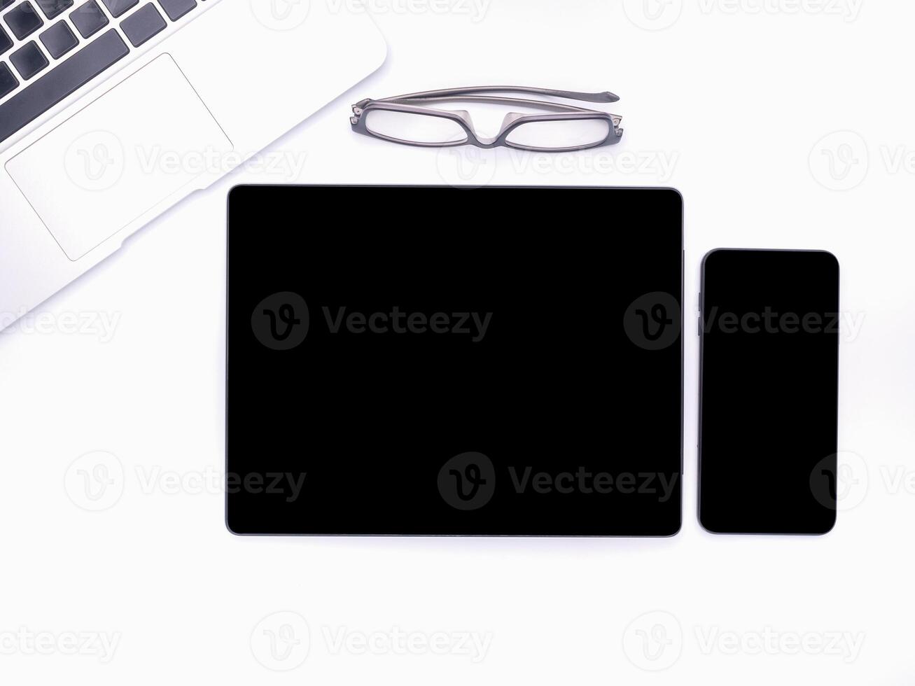 Top view of a blank tablet, smartphone, laptop, and glasses isolated on white background. Space for text. Technology and communication concept photo