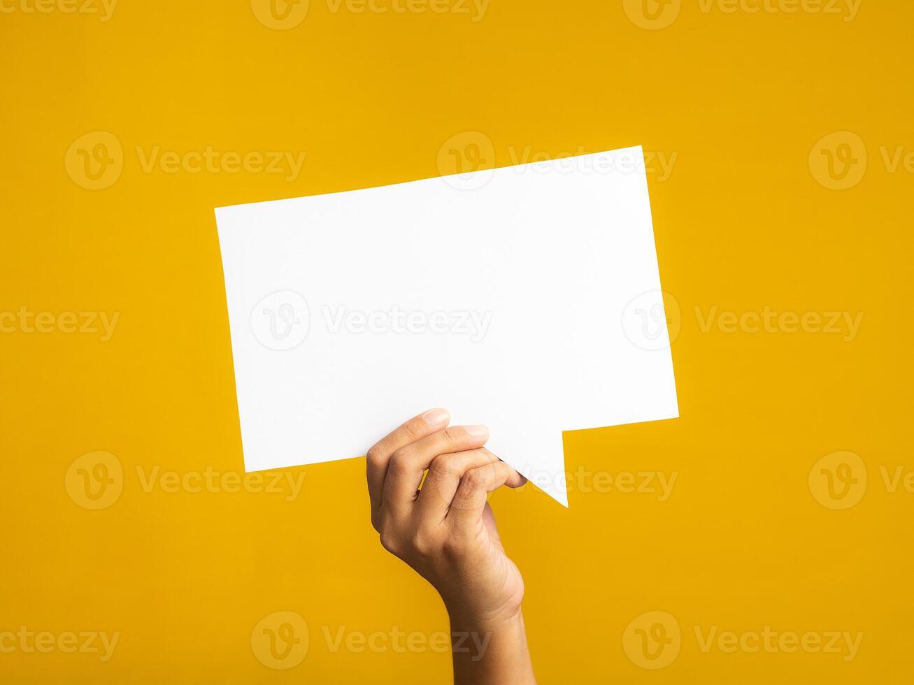 Speech bubble concept. Hand holding an empty speech balloon on yellow background with copy space for text. Close-up photo