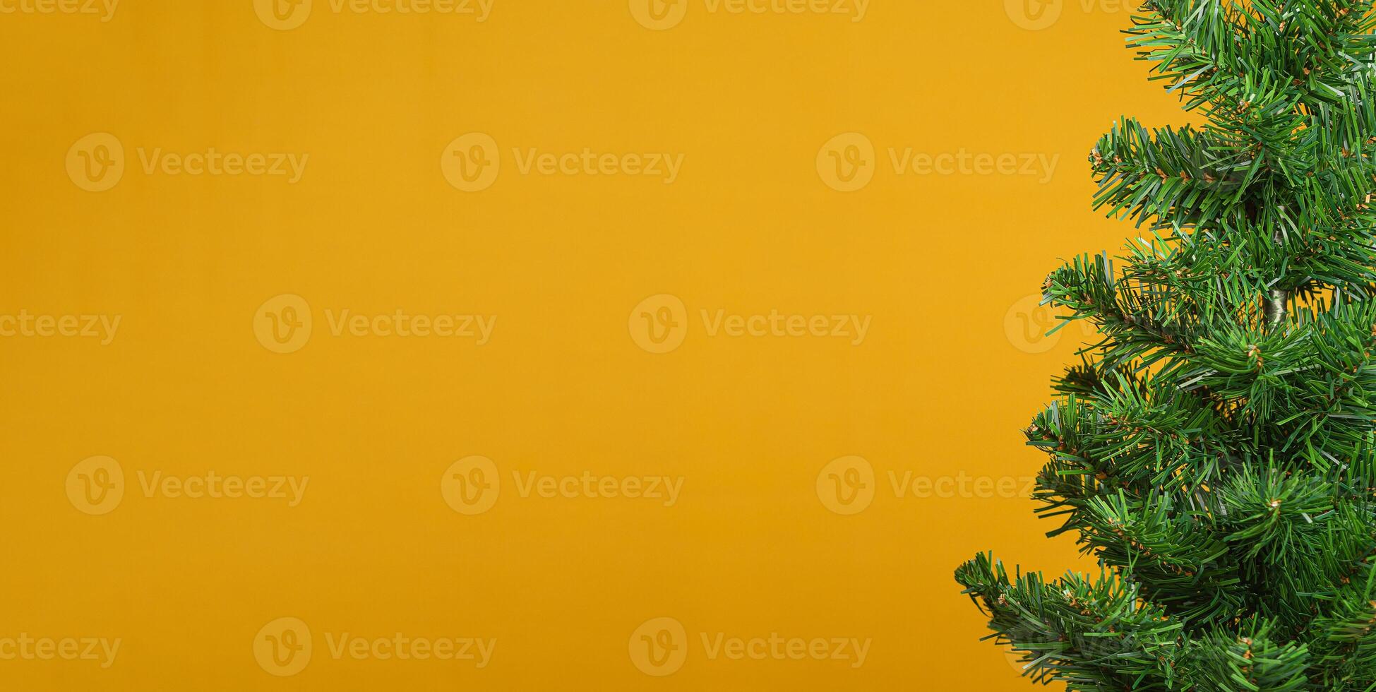 Part of Christmas tree over a yellow background with copy space for text photo